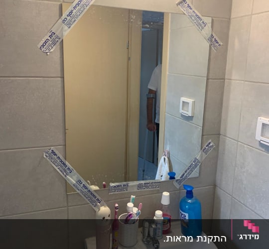 מראה עם מדבקות על הקצוות בחדר אמבטיה